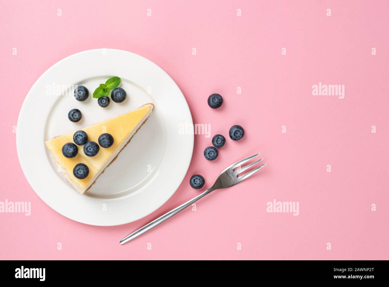 Cheesecake Slice On Plate With Blueberries, Top view, Pink Background. Trendy Fashion Dessert Stock Photo