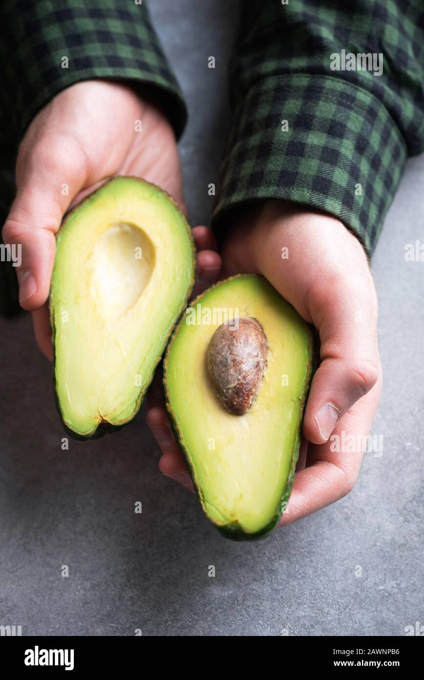 Male hands holding avocado halves. Healthy Eating, healthy lifestyle, vegetarian diet concept Stock Photo