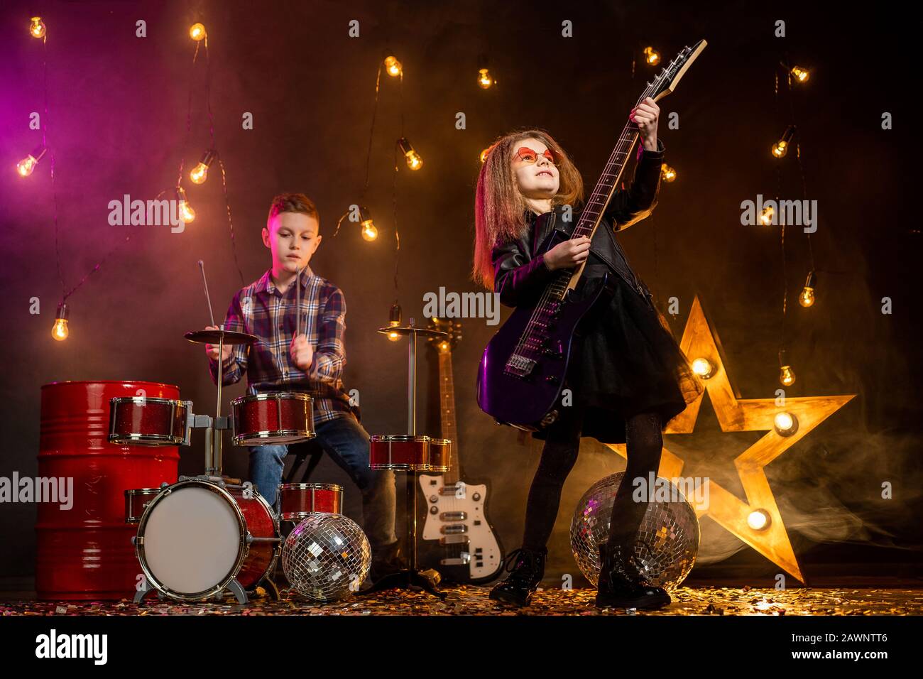 Kids pretending to be in a rock band and play and sing at studio or