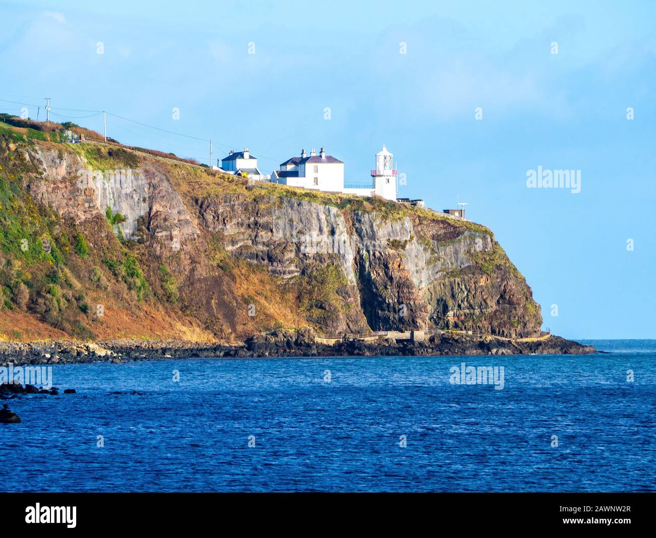 Black Head Lighthouse in Whitehead village on a steep cliff on the Atlantic coast in County Antrim, Northern Ireland, UK Stock Photo