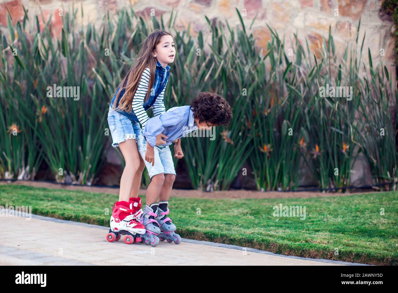 A Girl Training Her Friend Boy Roller Skate In The Park Children