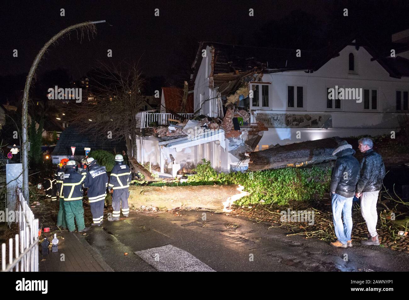 Hamburg, Germany. 09th Feb, 2020. Emergency services of the fire brigade and the residents of the house inspect the damage. A tree toppled over due to the passage of storm 'Sabine' by the strong wind and severely damaged parts of an apartment building in Hamburg's Treppenviertel. Credit: Jonas Walzberg/dpa/Alamy Live News Stock Photo