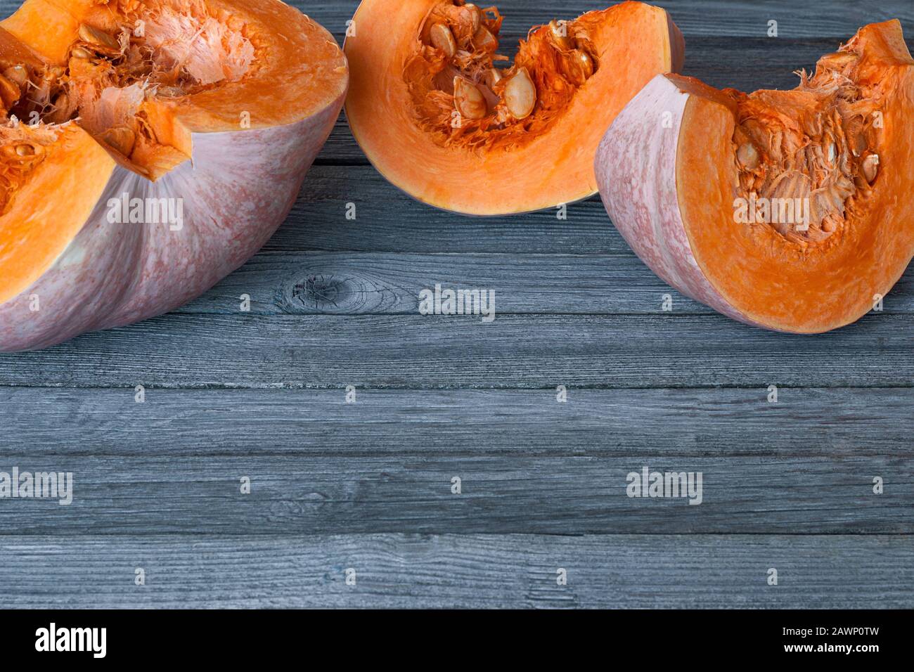 cut pumpkin slices on gray wooden table with copy space Stock Photo
