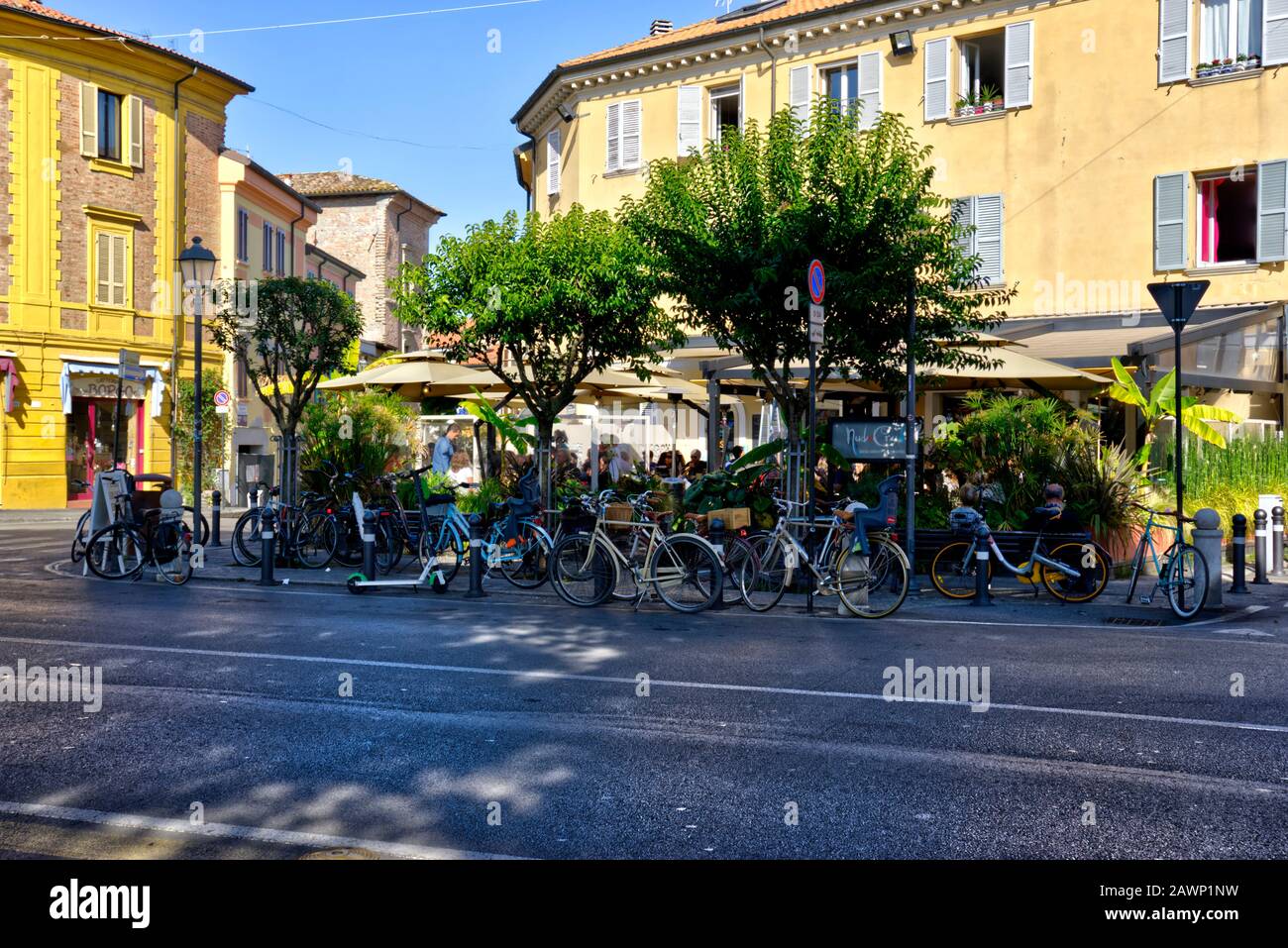 Rimini, Italy - October 20, 2019: Group of people eat and drink outside cafe with numerous parked bicycles and an e-scooter Stock Photo