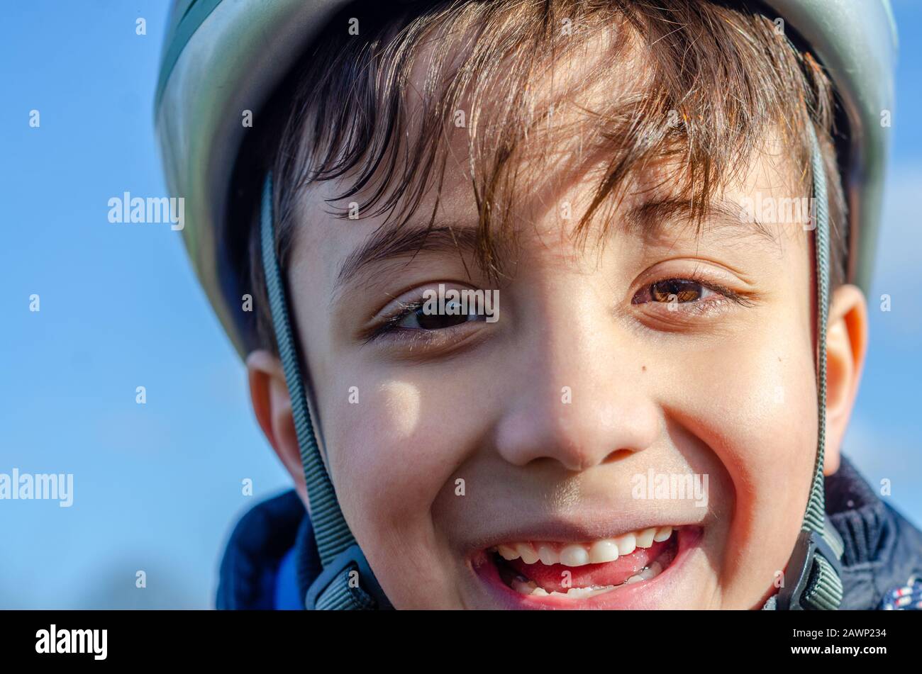 Portrait of a young boy outdoors wearing a bicycle helmet and smiling. Stock Photo