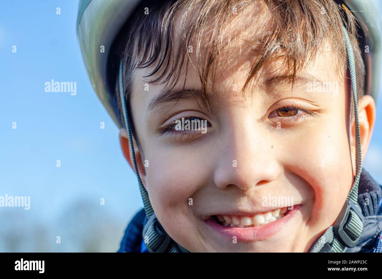Portrait of a young boy outdoors wearing a bicycle helmet and smiling. Stock Photo