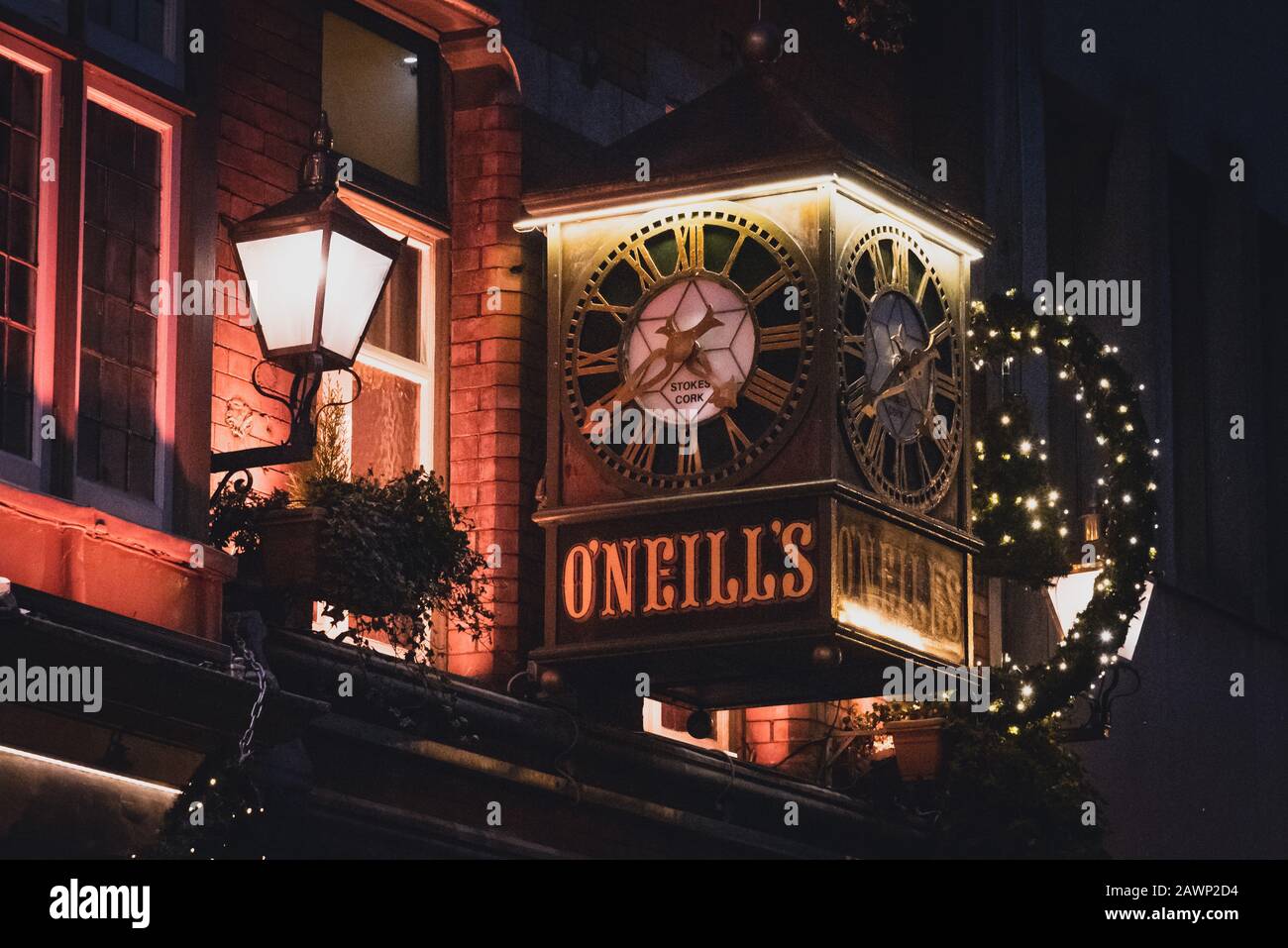 DUBLIN, IRELAND, DECEMBER 24, 2018: View of the clock on the exterior of the O'Neill's Pub and Kitchen on Suffolk Street, dimly lit and decorated for Stock Photo