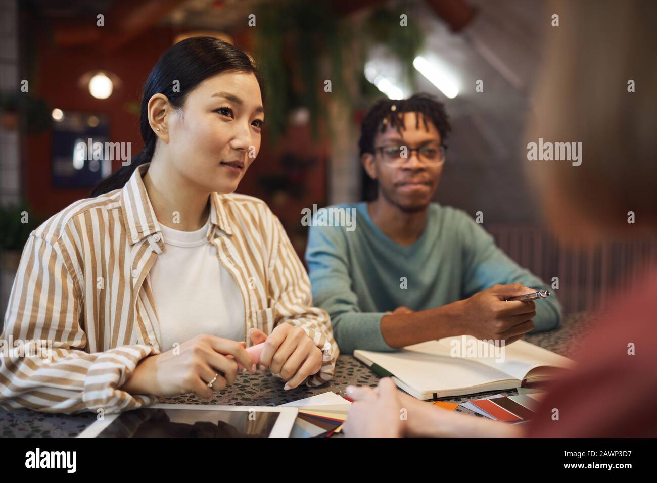 Multi-ethnic group of three business people working on project while sitting at table in cafe, copy space Stock Photo