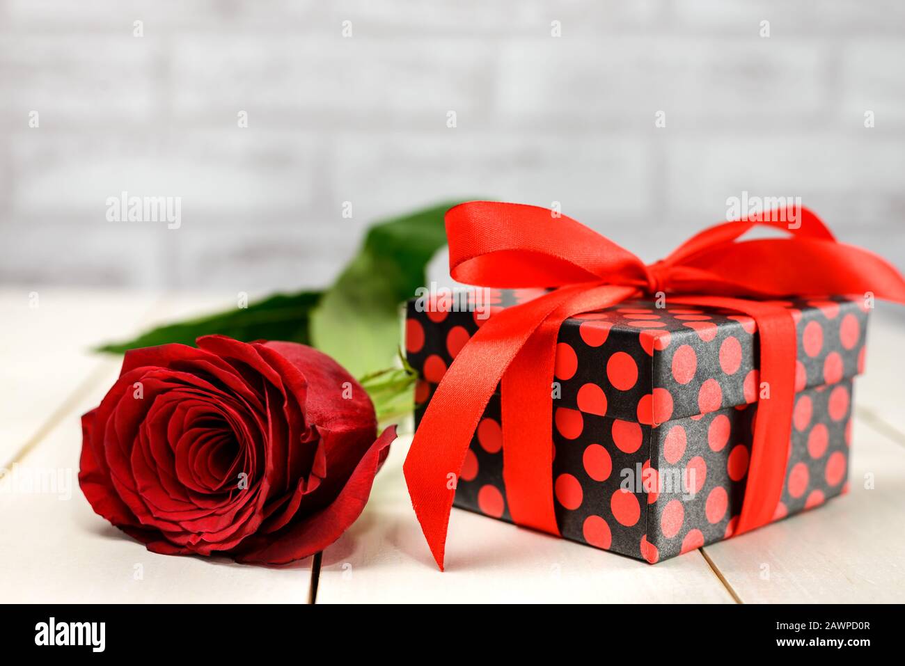 Red rose and gift box on white wooden table with copy space for text. Valentine's Day and Women's Day card concept. Stock Photo
