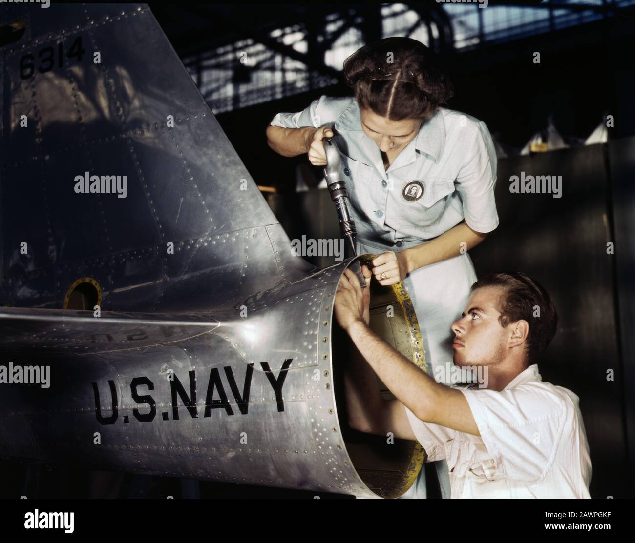 Mrs. Virginia Davis, Riveter in Assembly and Repair Department, supervising  Charles Potter, NYA Trainee from Michigan, at Naval Air Base, Corpus  Christi, Texas, USA, photograph by Howard R. Hollem, U.S. Office of