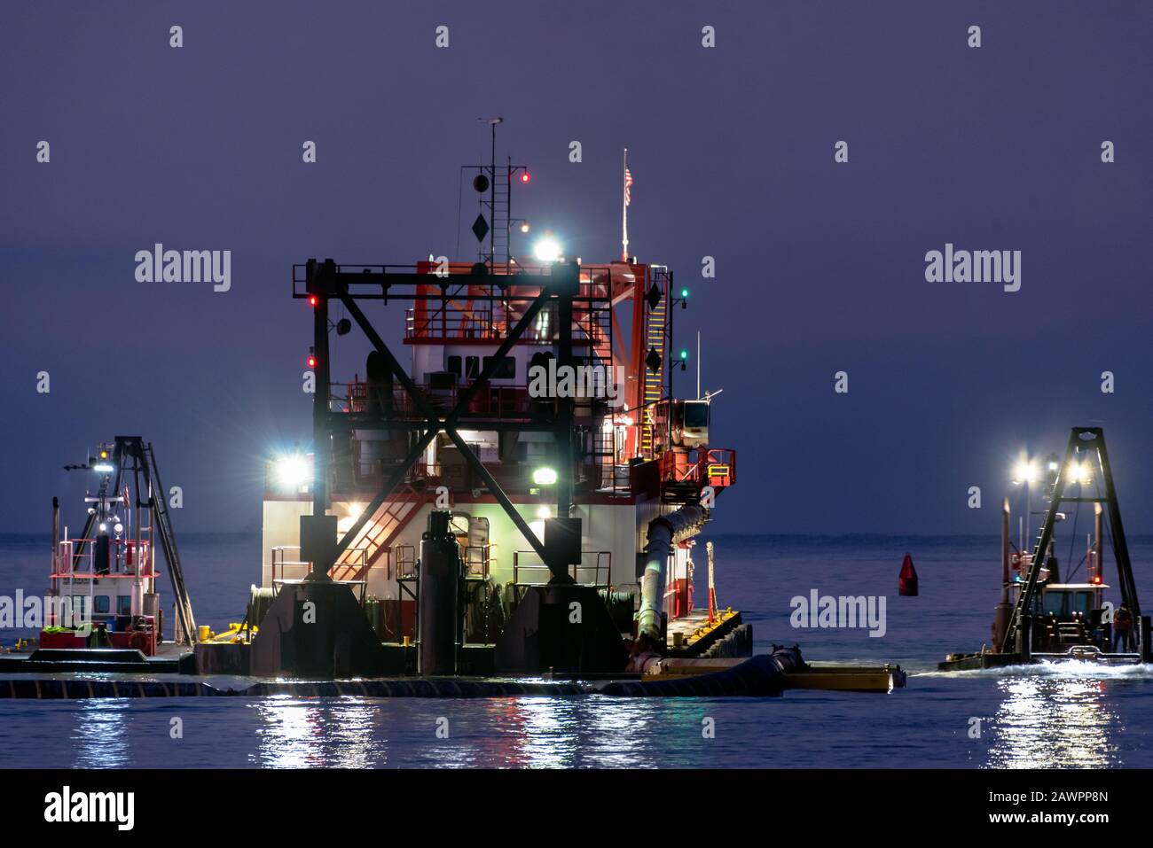 Dredging rig in the Ventura Harbor mouth works as dawn breaks on