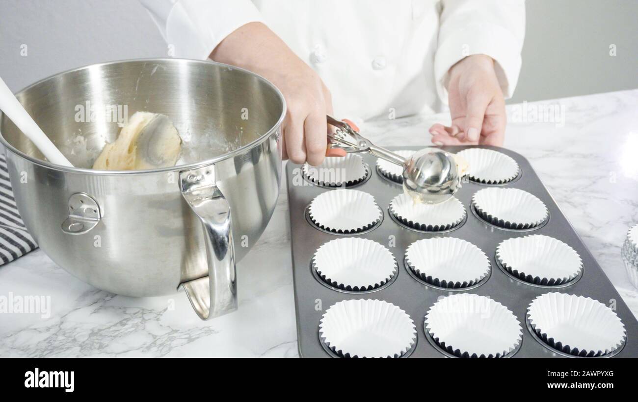 Step by step. Scooping batter with batter scooper into cupcake pan lined  with paper cupcake liners Stock Photo - Alamy