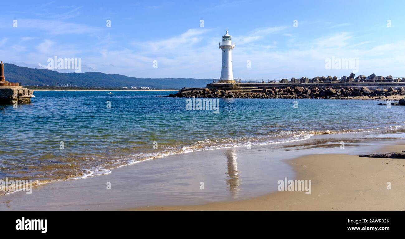 view across the Belmore basin beach to the old Wollongong Harbour Lighthouse located on the end of the breakwater at harbour entrance. Stock Photo