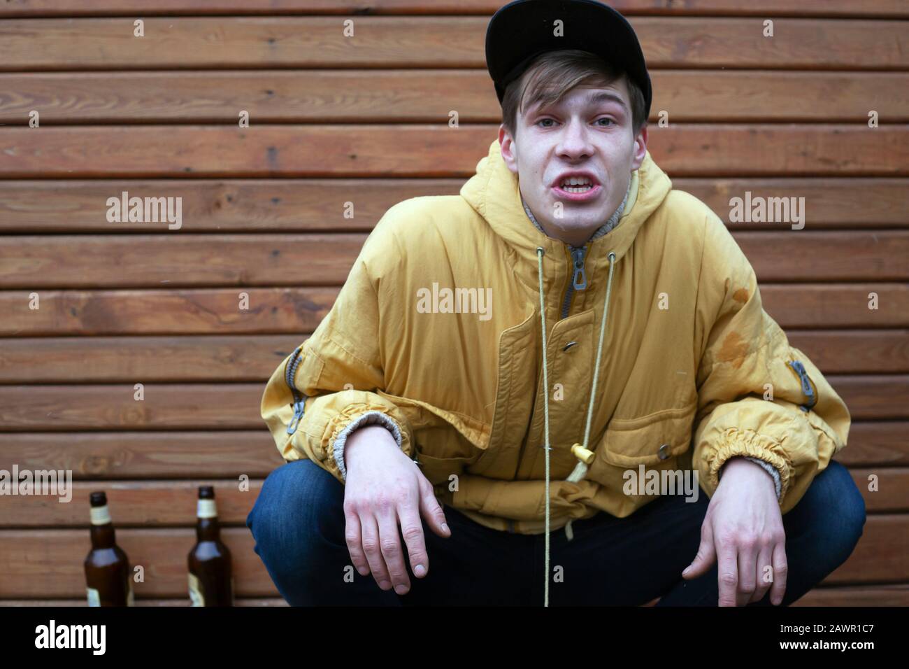 cheeky football fan got drunk beer. stylish young guy in a yellow jacket with an angry face swears. Stock Photo