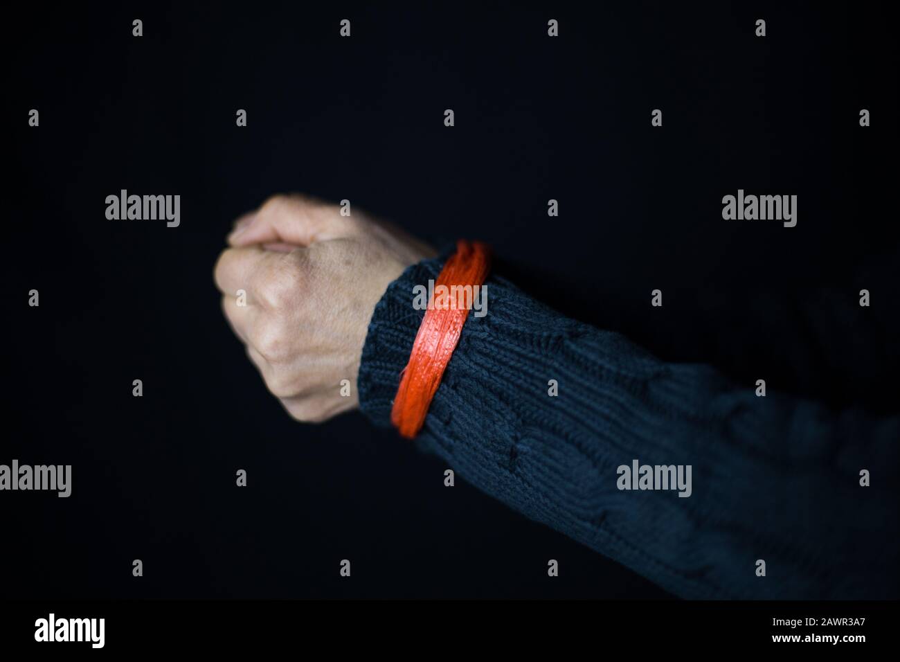 Middle-aged female's tied hands on a black background - women's right concept Stock Photo