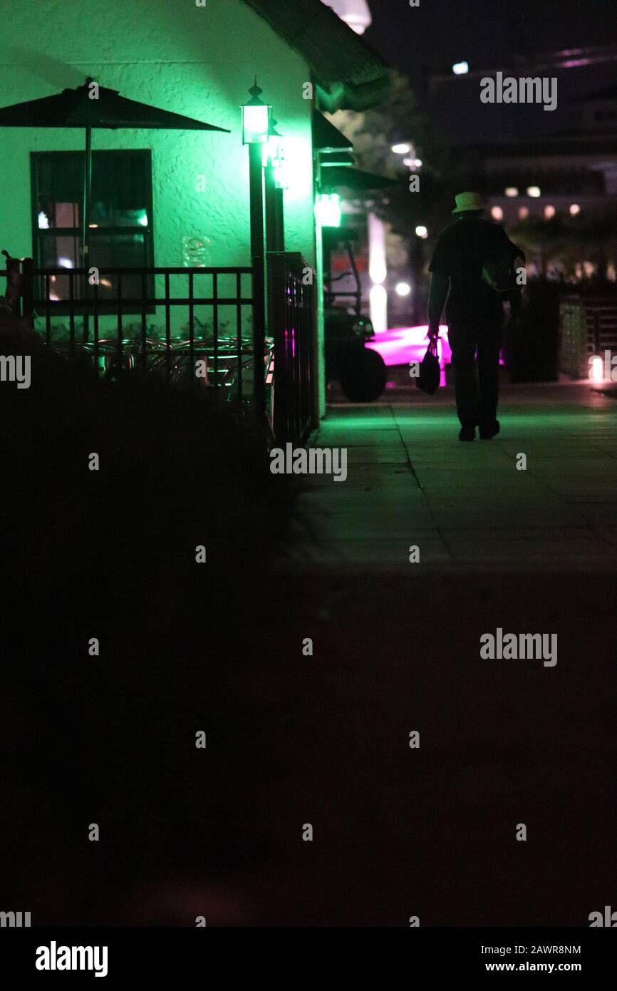 Vertical shot of a man walking through the city at night Stock Photo