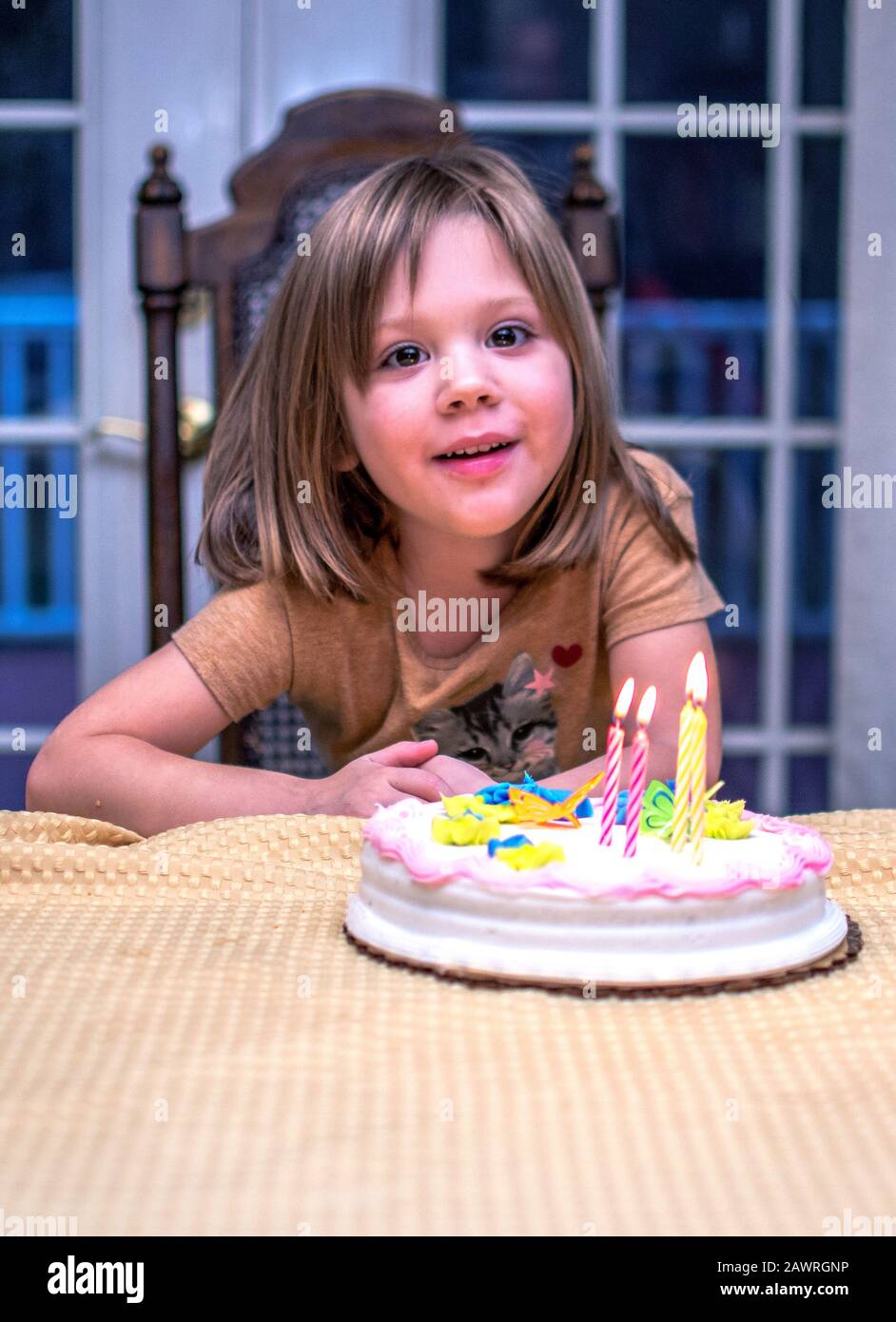 A proud little girl beams as family sings happy birthday and she gets to blow out 4 candles Stock Photo
