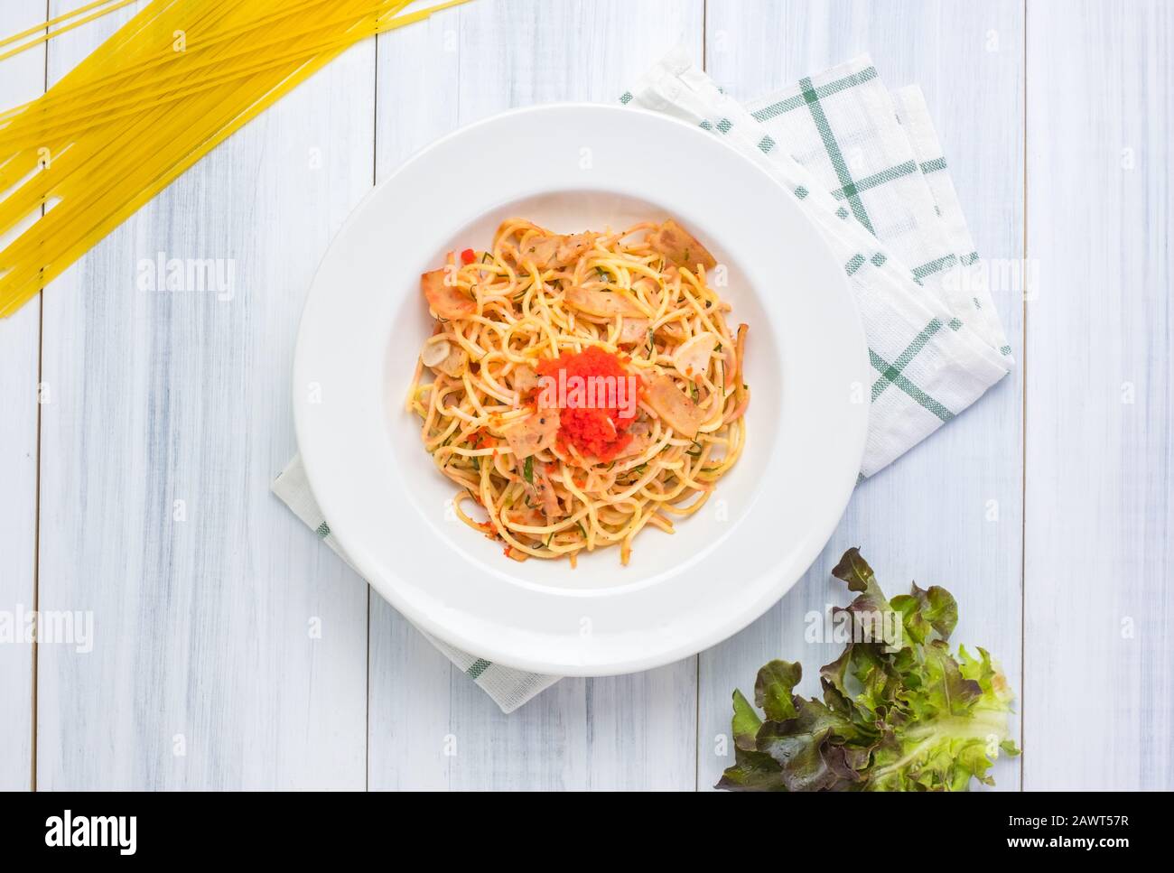 Delicious spaghetti spicy with tobiko with tablecloth on white wood plank table top with raw food material at background. Stock Photo