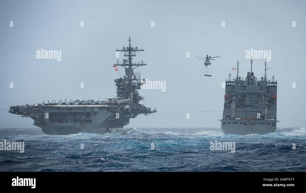 PACIFIC OCEAN (Feb. 4, 2020) A Eurocopter AS332 Super Puma carries ordnance between the dry cargo and ammunition ship USNS Carl Brashear (T-AKE 7), right, and the aircraft carrier USS Theodore Roosevelt (CVN 71) during a vertical replenishment-at-sea Feb. 4, 2020. The Theodore Roosevelt Strike Group is on a scheduled deployment to the Indo-Pacific. (U.S. Navy photo by Mass Communication Specialist 3rd Class Nicholas V. Huynh) Stock Photo