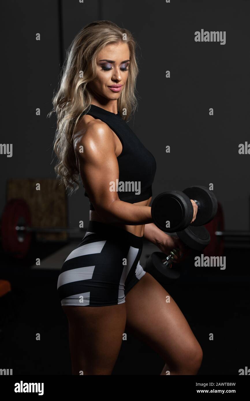 Young Woman Exercising Biceps With Dumbbells In The Gym And Flexing Muscles  - Muscular Athletic Bodybuilder Fitness Model Doing Dumbbell Concentration  Stock Photo - Alamy