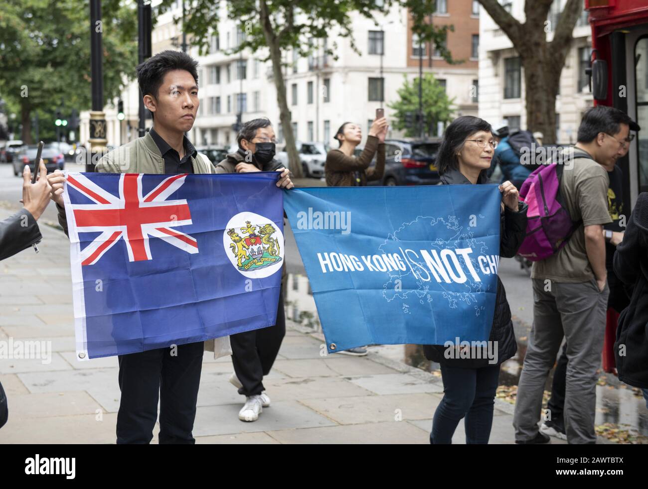 London, UK. 28th July, 2019. Protesters hold the Sino-British flag(L) and a flag saying 'Hong Kong is not China' outside the Chinese Embassy in London.With a hired red London routemaster bus, the protesters travelled round the city spreading the slogan Stand with Hong Kong. The protesters asked 'Will Boris surrender to China?''While creating a 'Lennon Wall'' of Post-it notes on the side of the bus and a poster of HK Chief Executive Carrie Lam in the style of those protesting in Hong Kong. Credit: Jayne Russell/ZUMA Wire/Alamy Live News Stock Photo