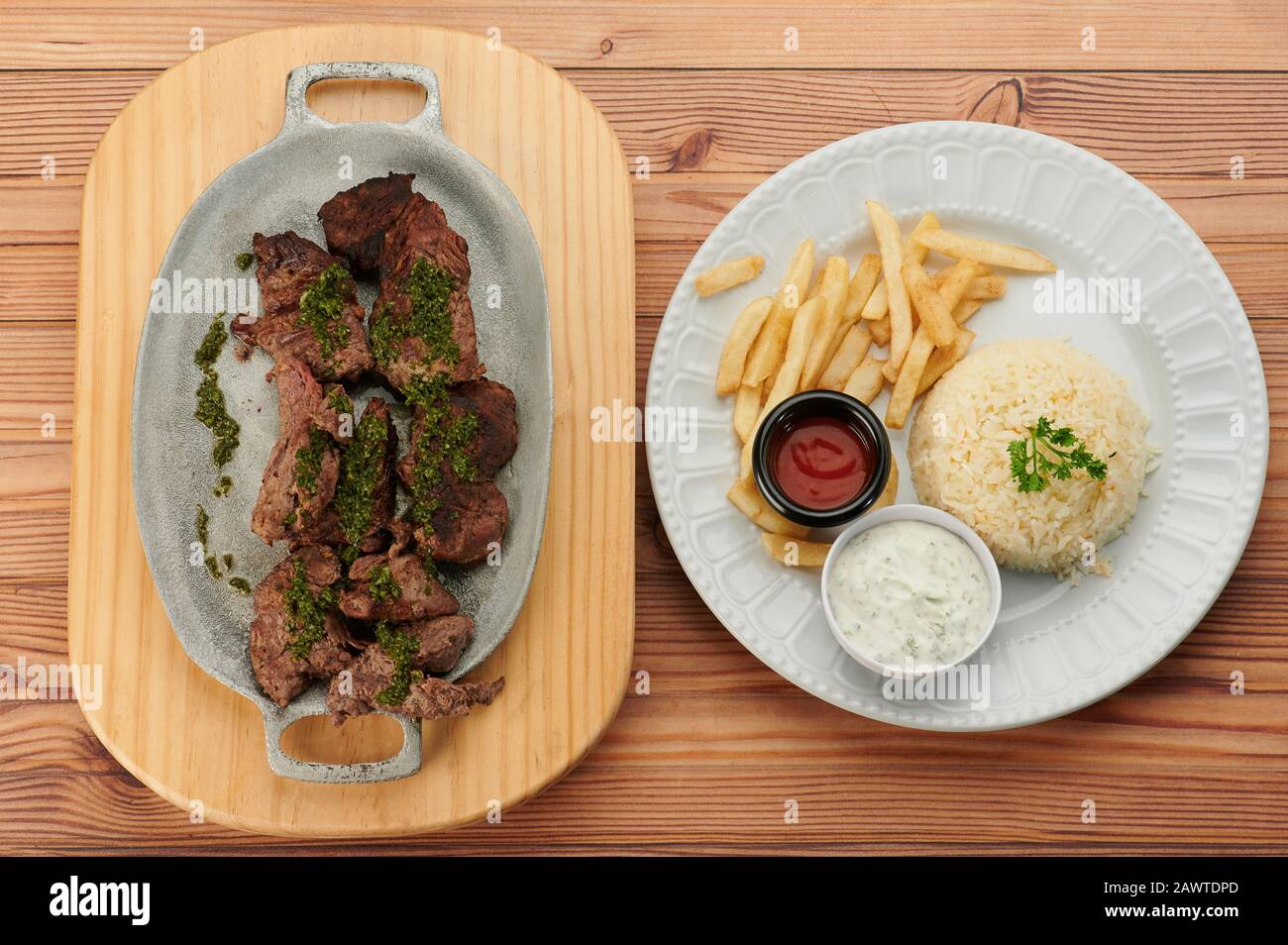 Steak with rice and french fries on 2 plates above view in wooden table Stock Photo