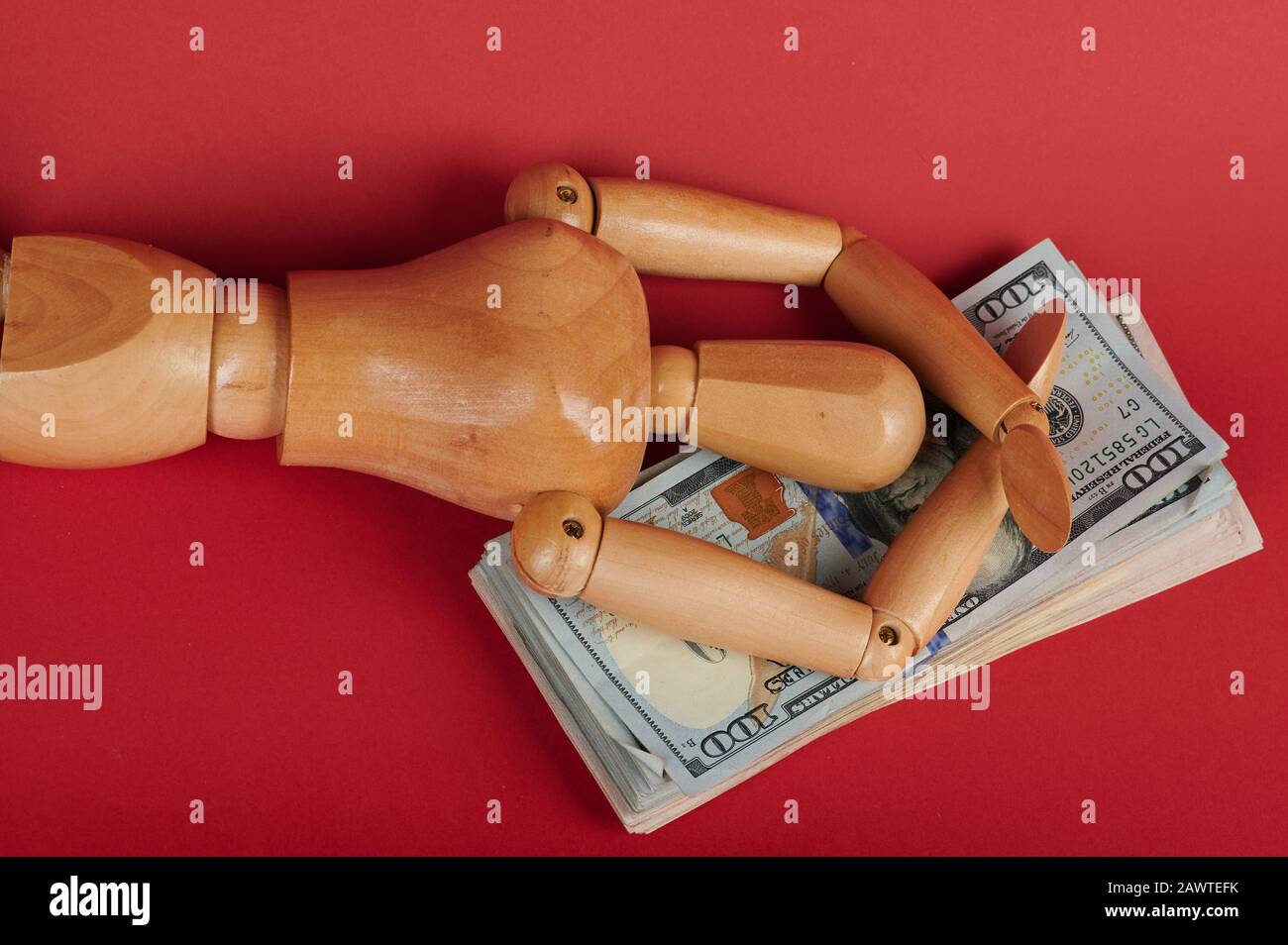Wooden man lay on dollar pile in happy pose Stock Photo