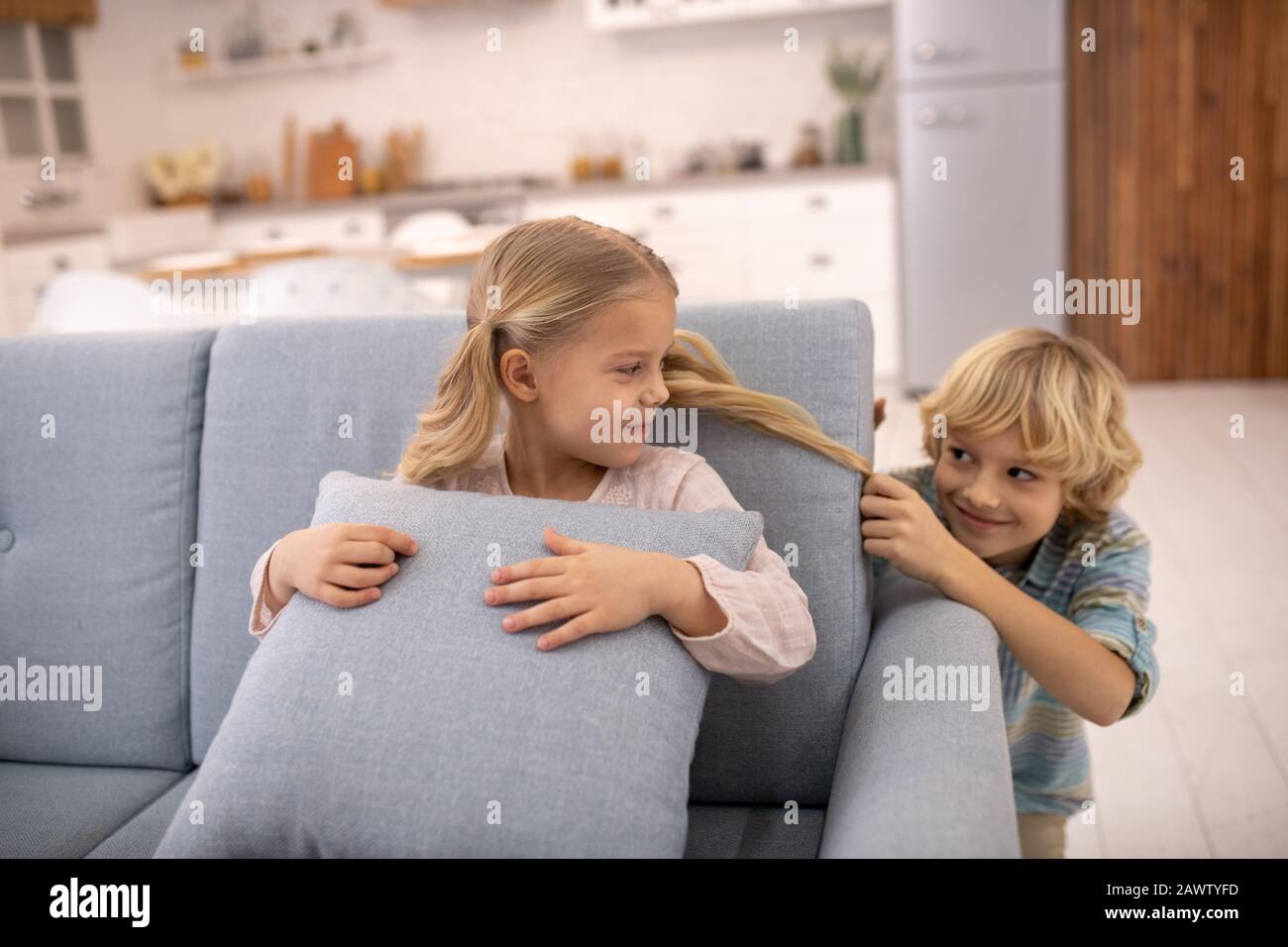 Boy pulling girls ponytail from behind, teasing and feeling joyful