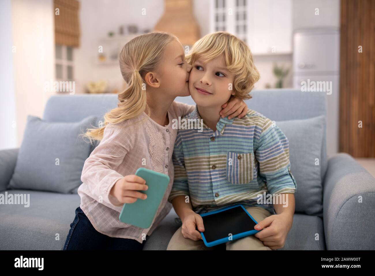 Girl kissing and embracing boy, both are happy Stock Photo