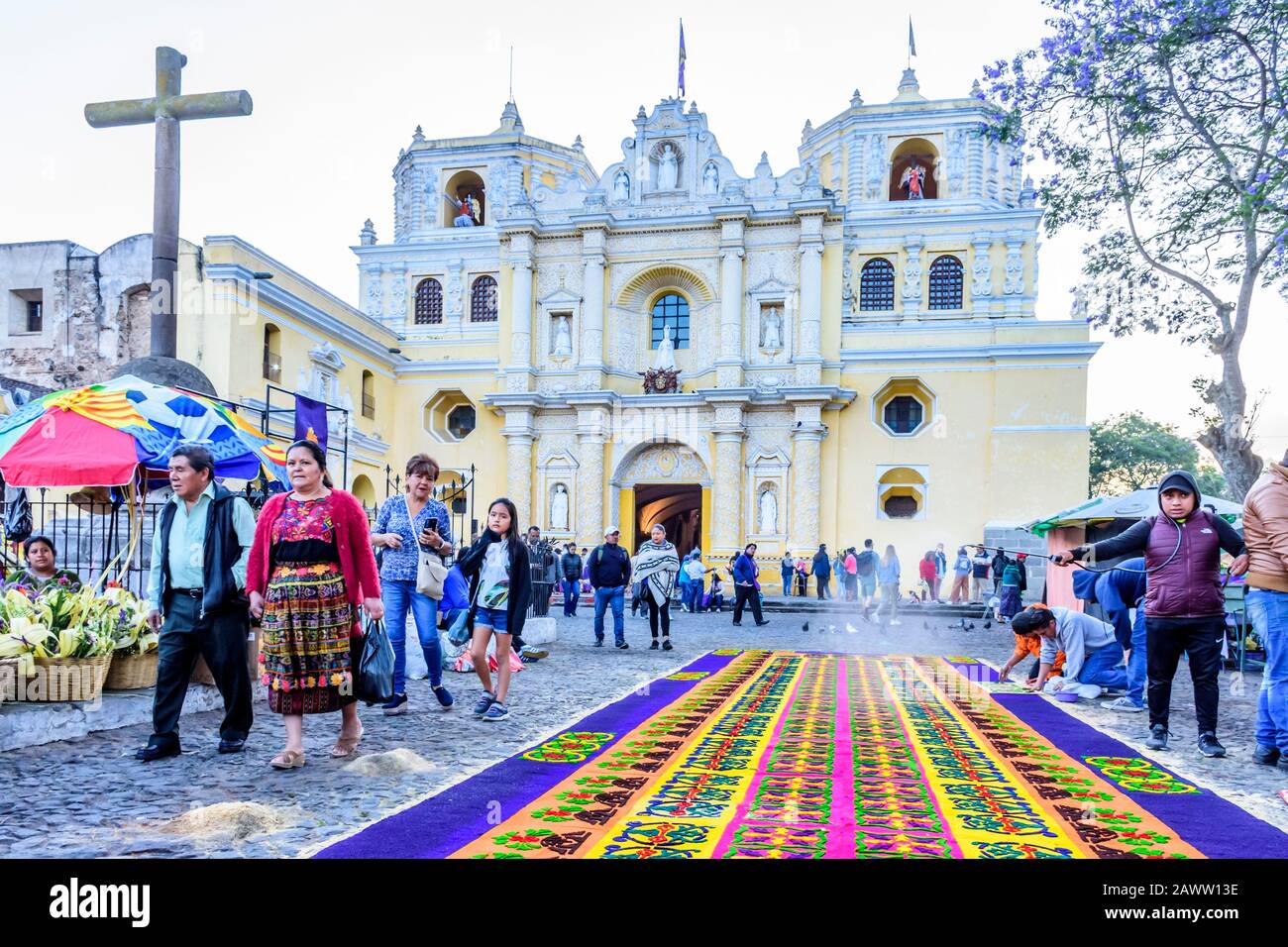Antigua, Guatemala -  April 14, 2019: Making dyed sawdust Palm Sunday procession carpet outside La Merced church in UNESCO World Heritage Site. Stock Photo
