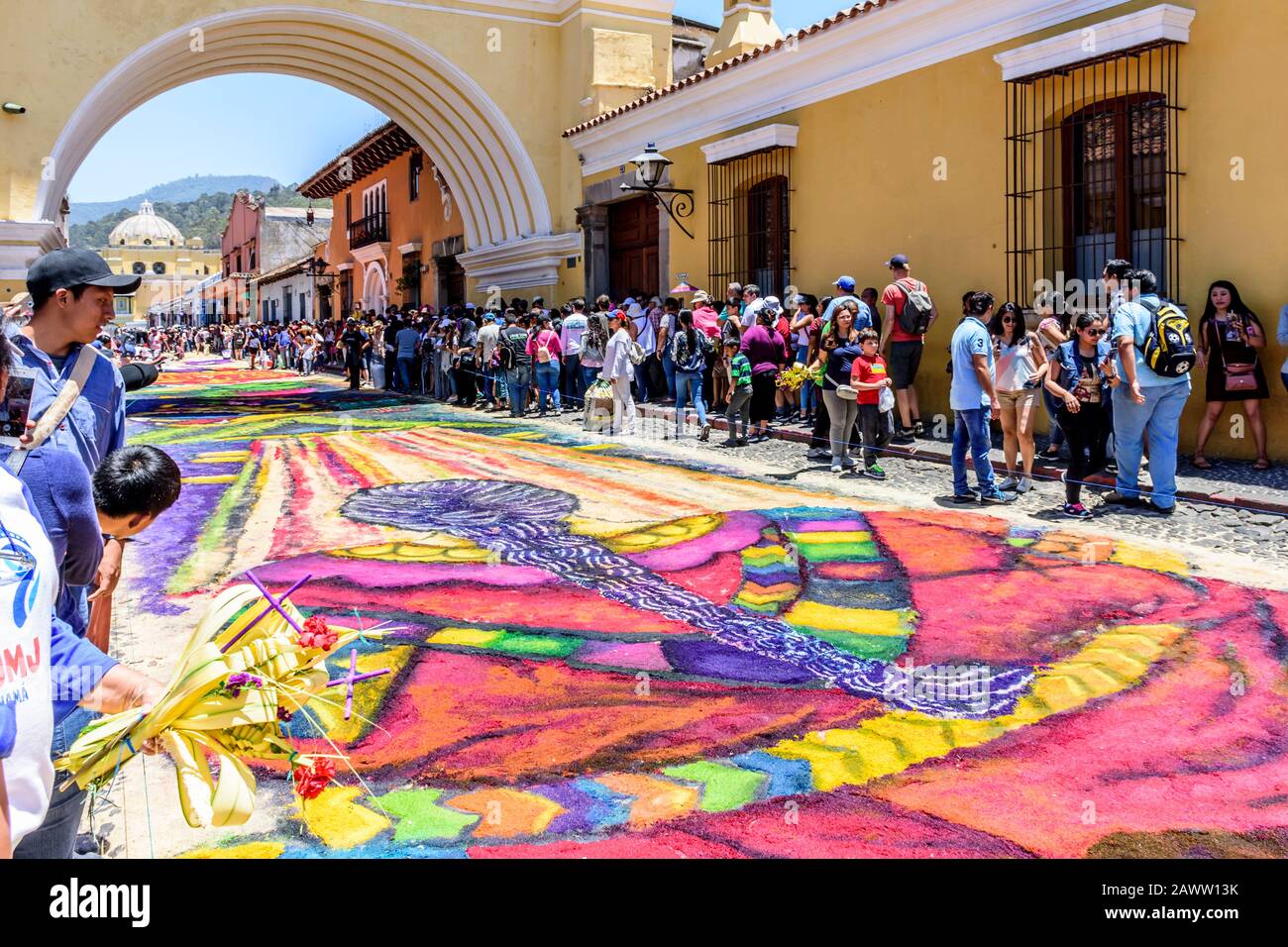 Antigua, Guatemala -  April 14, 2019: Making dyed sawdust Palm Sunday procession carpet under Arco de Santa Catalina in UNESCO World Heritage Site. Stock Photo