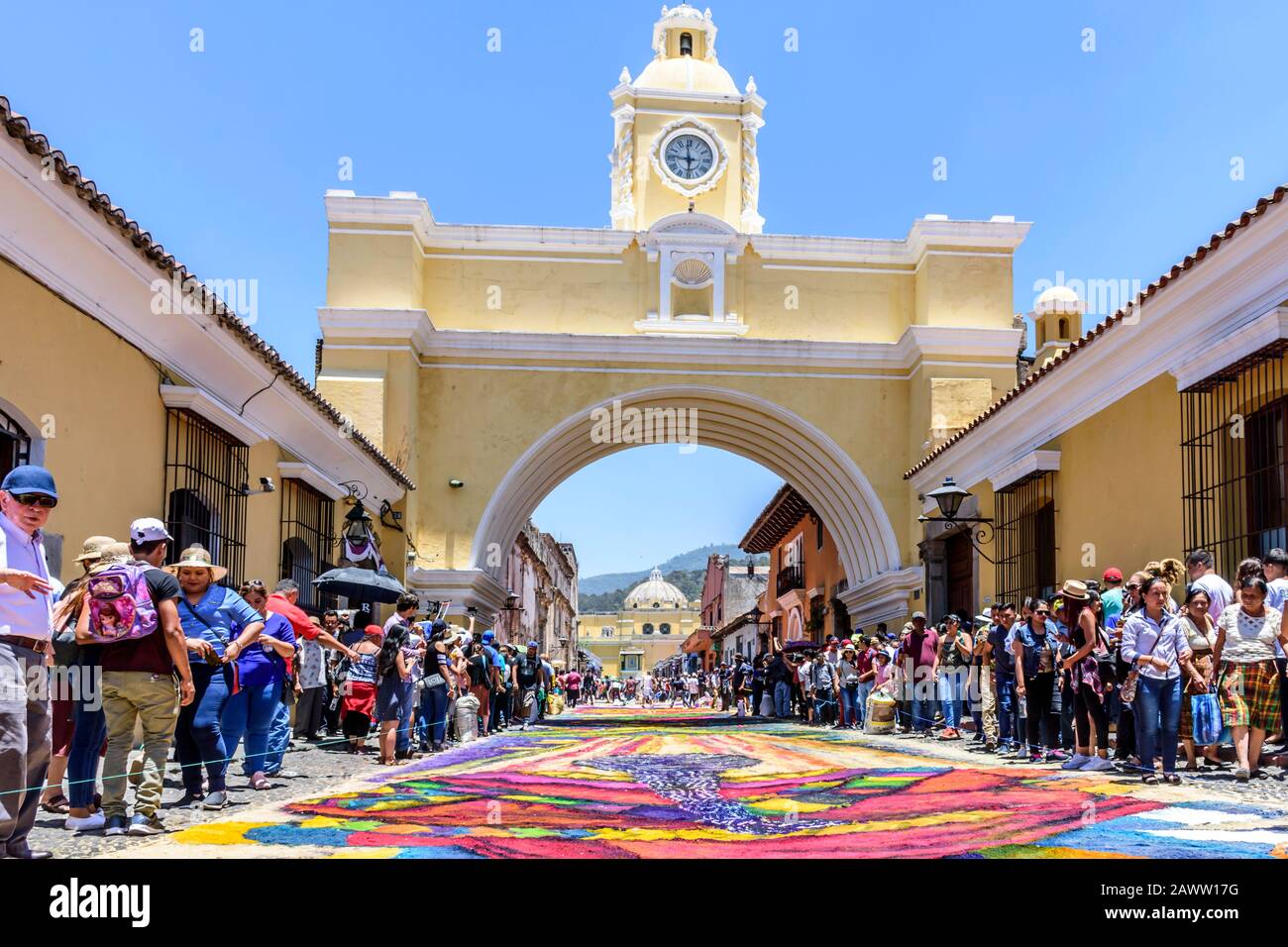 Antigua, Guatemala -  April 14, 2019: Making dyed sawdust Palm Sunday procession carpet under Arco de Santa Catalina in UNESCO World Heritage Site. Stock Photo