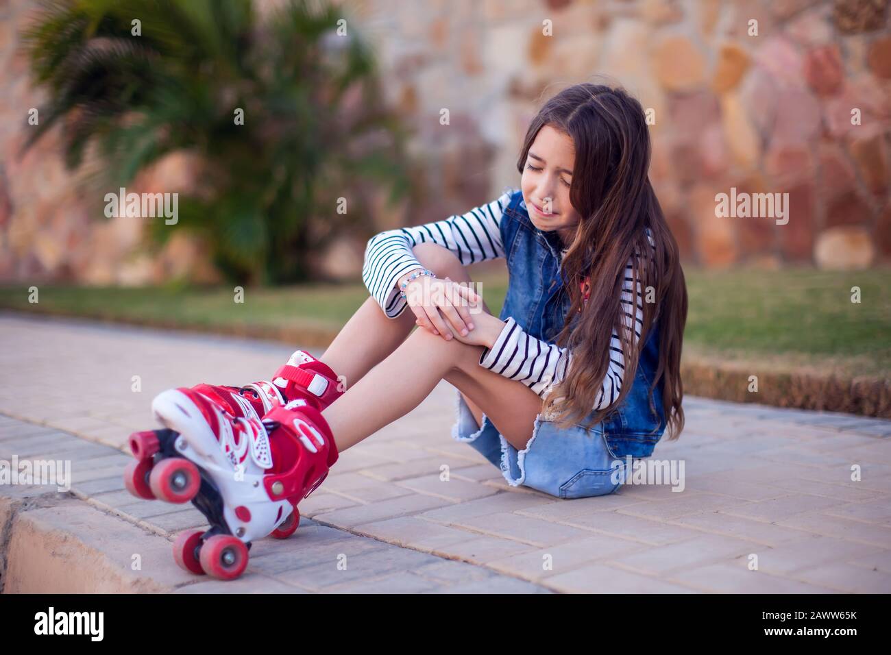 A kid girl on rollerskates fell down and feels pain. Children, leasure