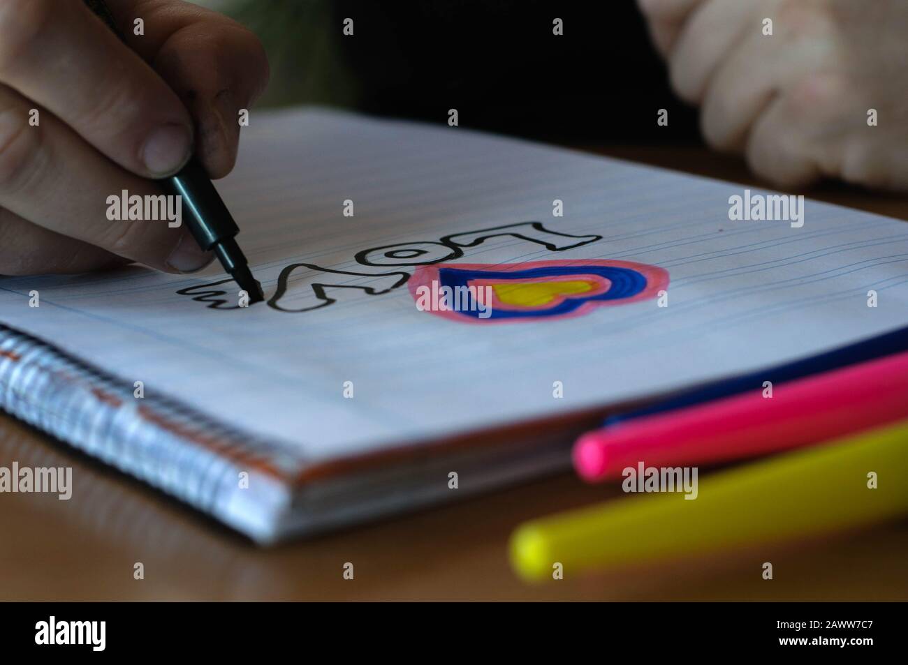 man's hand draws heart and inscription love on a white sheet of paper ...