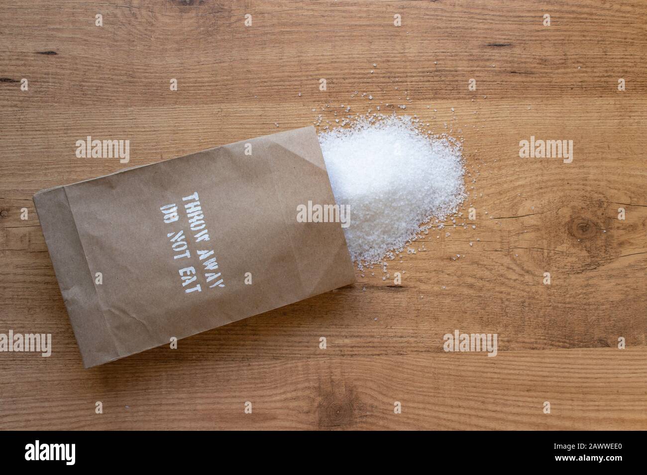 Salt in the paper pack on the table. 'Throw away, do not eat' added salt intake health warning on the packet. Stock Photo