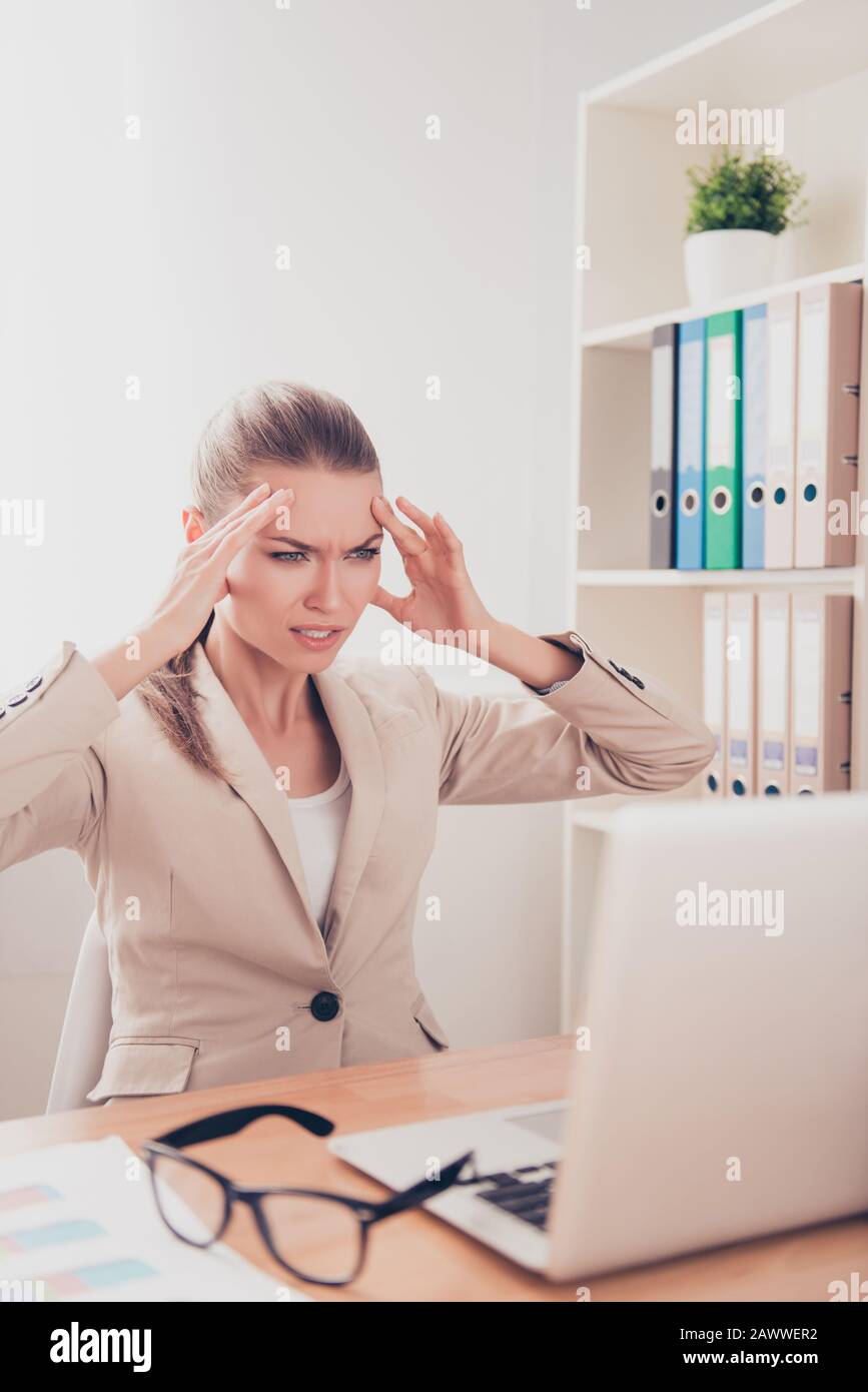 Overworked businesswoman feeling strong headache and can't work Stock Photo