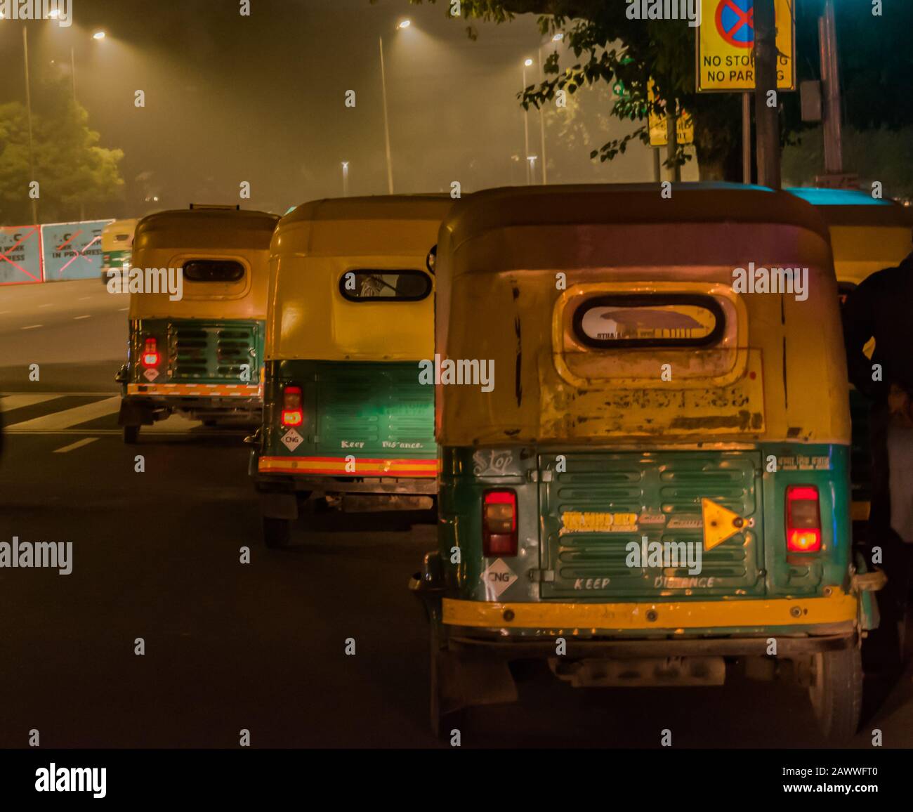 Three wheeled, CNG powered Iconic auto rickshaws of India plying on the roads of Delhi downtown during night hours, for commute in foggy Winter nights Stock Photo