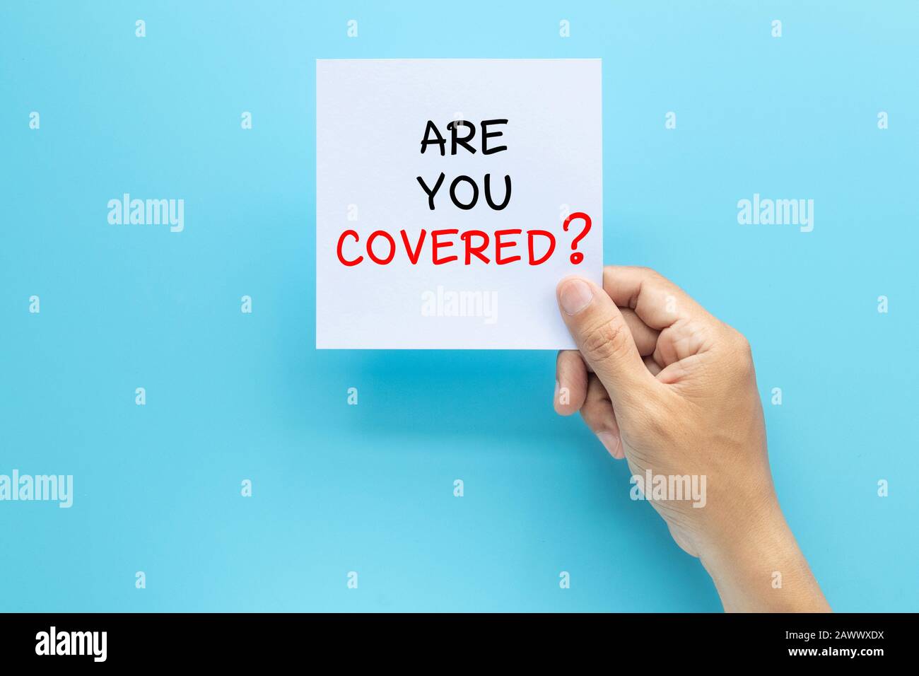 hand holding paper with question ARE YOU COVERED? isolated on blue background with copy space. travel insurance concept Stock Photo