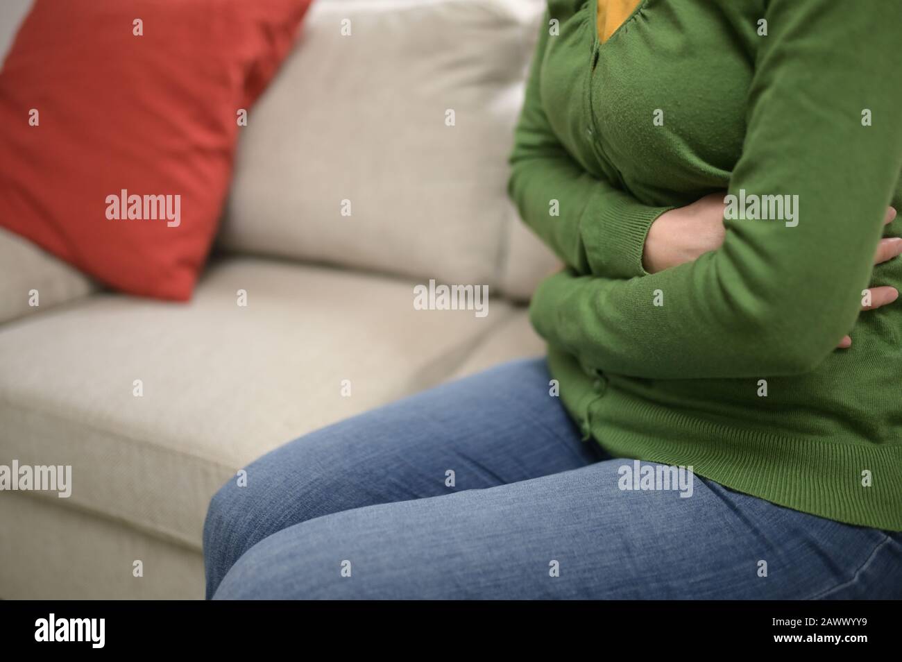 Woman Hands On Front Stomach Painful on Couch Stock Photo