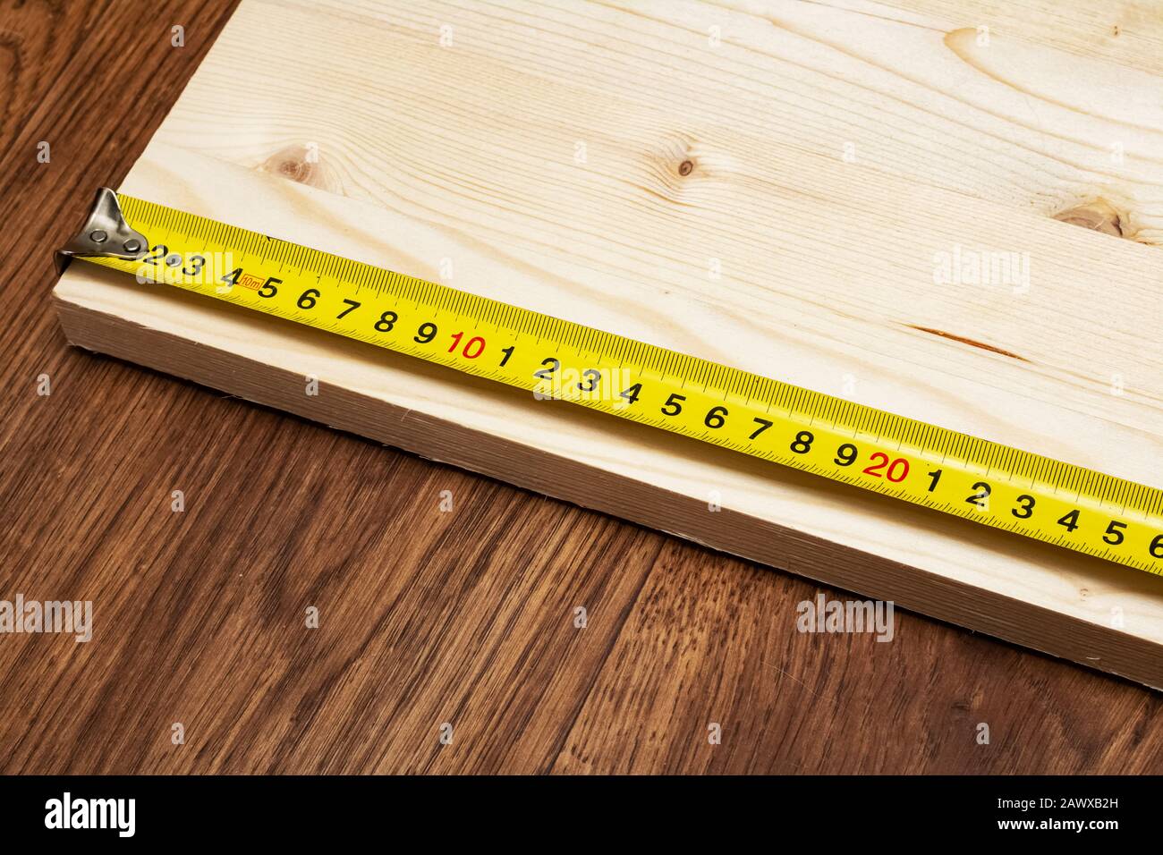 Measuring a wooden board with a tape measure Stock Photo Alamy
