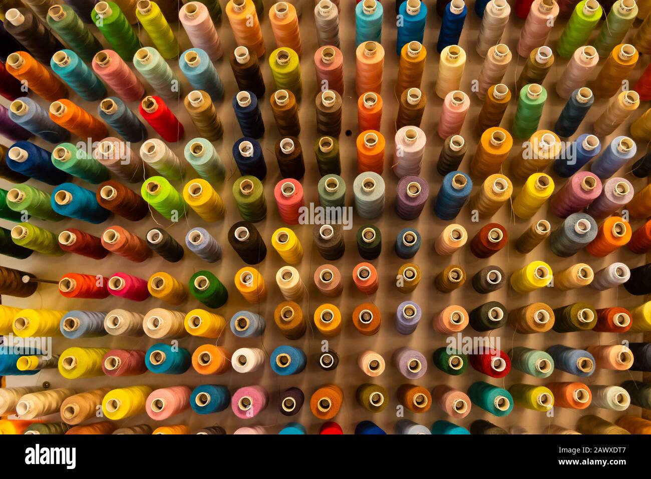 A lot of sewing thread in different colors, sewing thread sorted on a wall Stock Photo