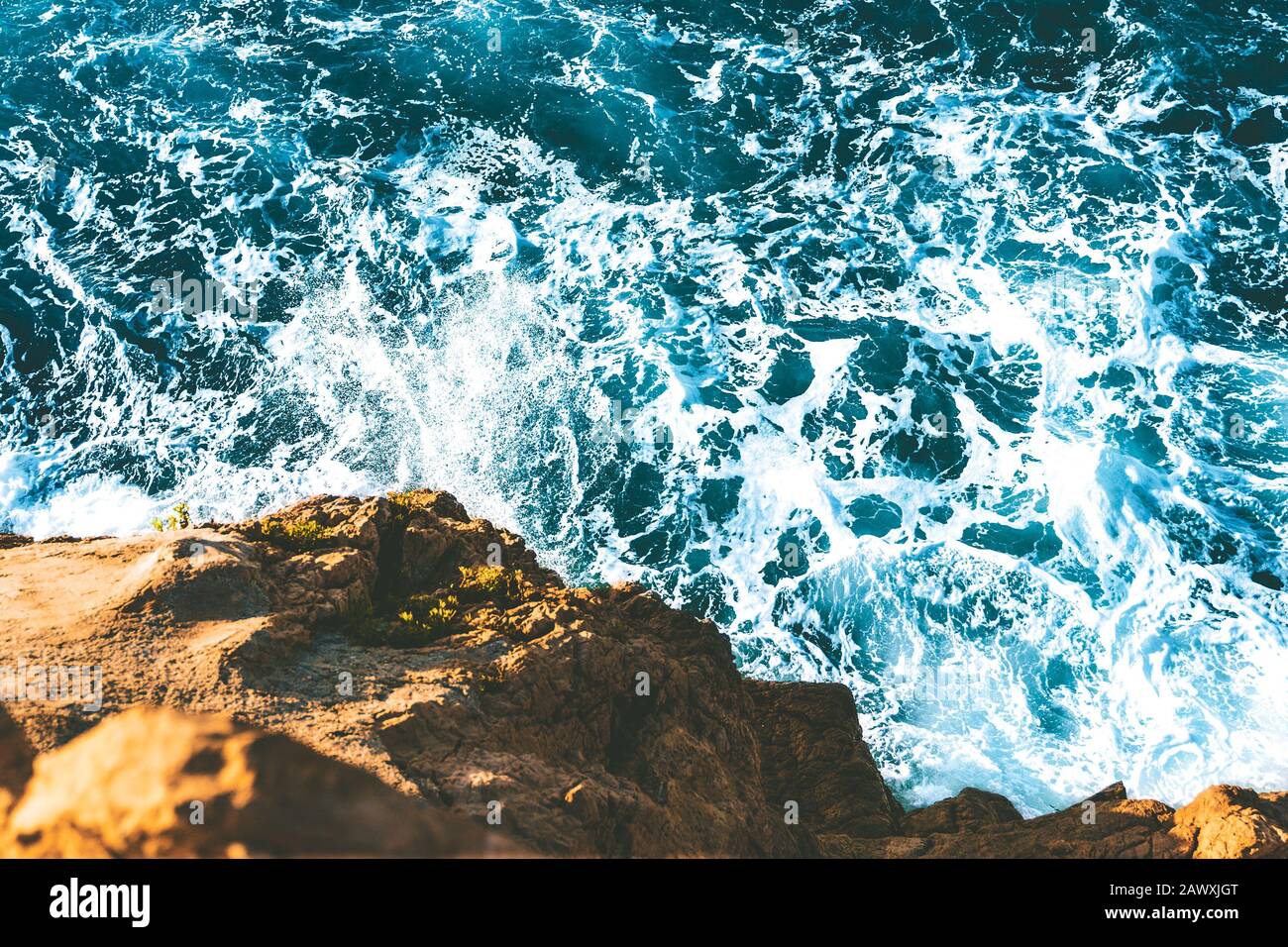 top view of sea waves hitting rocks on the beach with turquoise blue ...