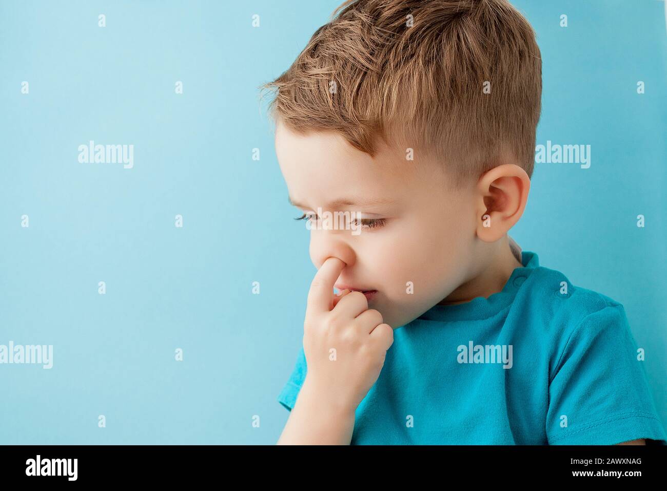 Little caucasian boy picking his nose on blue background Stock Photo