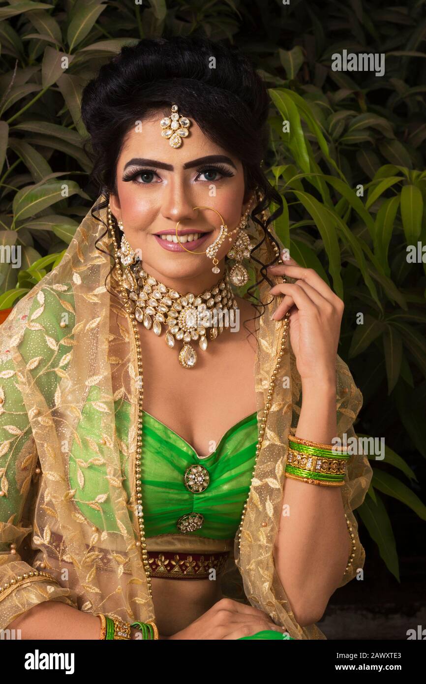 Female Model in traditional Indian Asian bridal wedding costume with makeup  and jewelry looking at camera closeup Stock Photo - Alamy