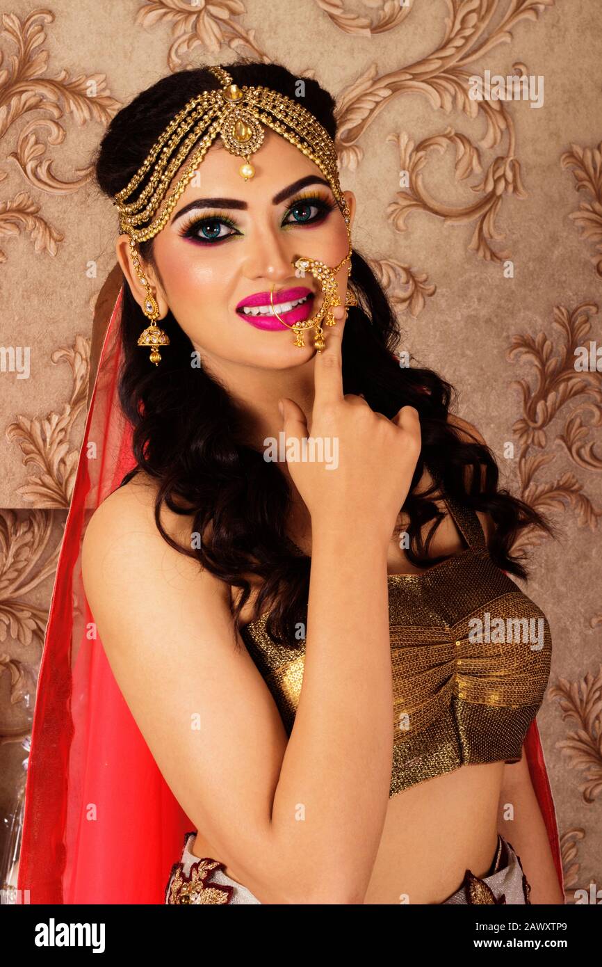 Portrait of an Indian bride wearing golden sari with heavy jewelry and  makeup. Closeup facing camera Stock Photo - Alamy