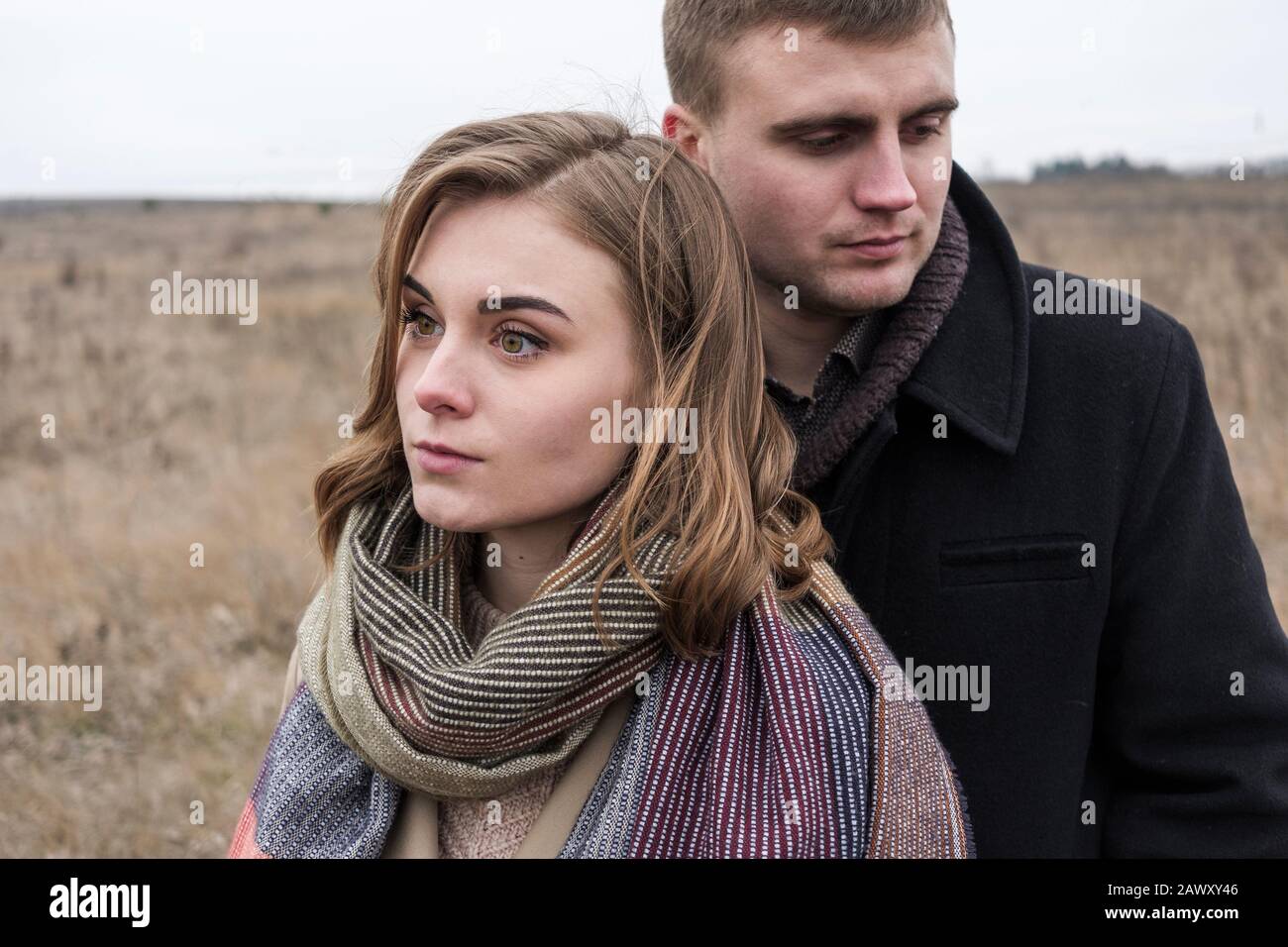 Serious troubled couple standing close together looking away from each other Stock Photo