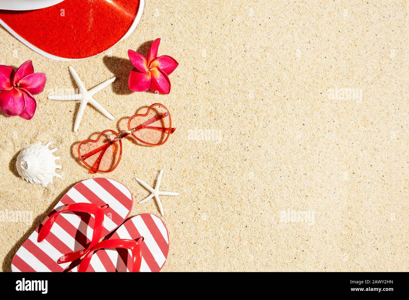 Sunglasses, Flip flops, plastic cap in red color in sand, top view with copy space, summer concept Stock Photo