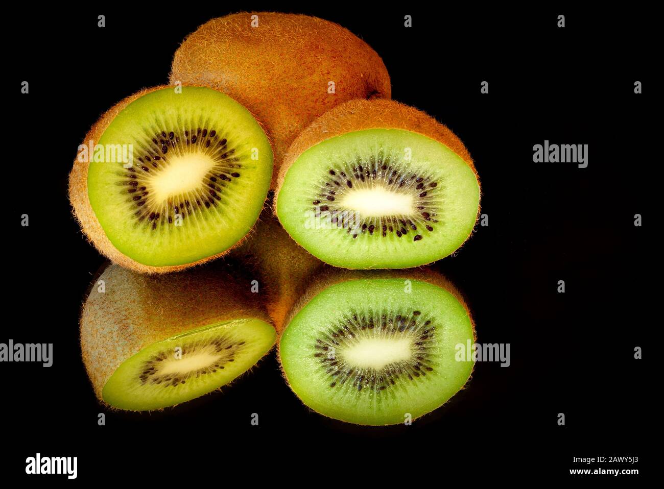 Kiwi fruit cut in half and sitting on a mirrored surface with