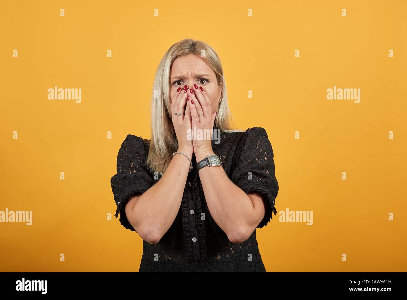 girl in black dress upset dissatisfied covered face with her hands from bad mood Stock Photo