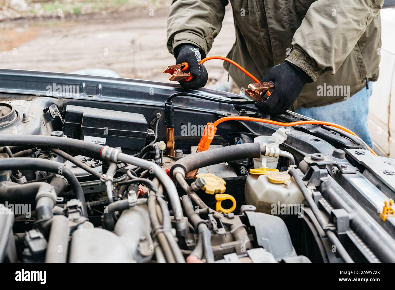 Mechanic engineer charging car battery with electricity using jumper